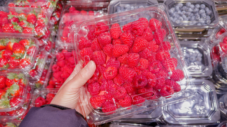 shopper holding raspberries in package at grocery store