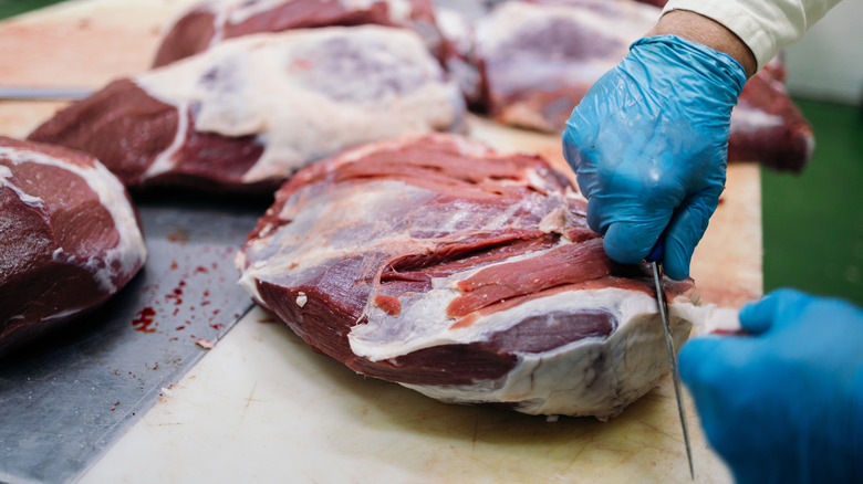 Butcher cutting trimming fresh meat