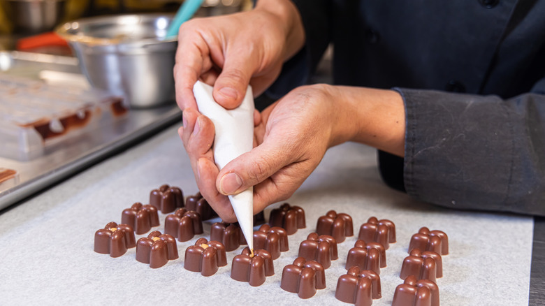 A chocolatier piping filling