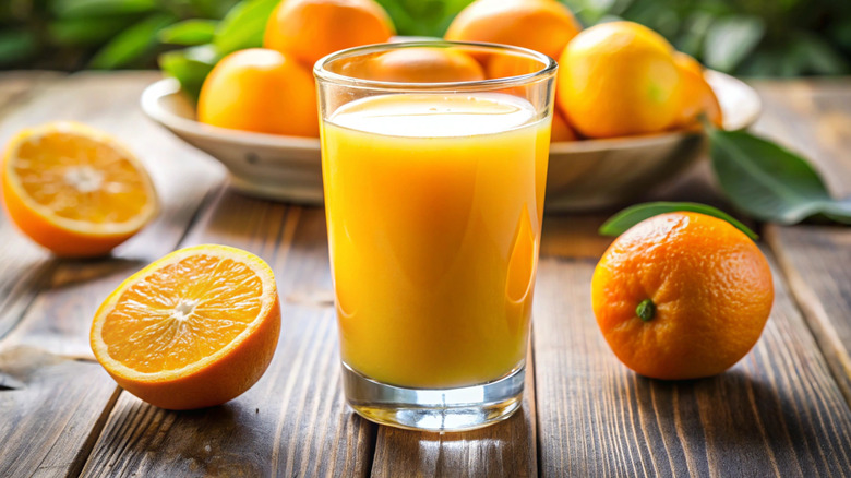 glass of orange juice with oranges in background