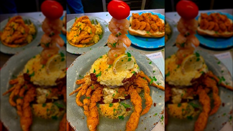 A fried softshell crab topped with sauce and a shrimp skewer on a restaurant table