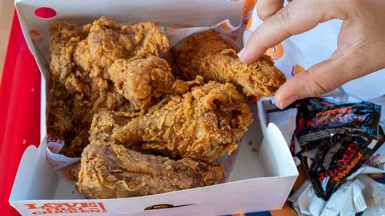 Hand grabbing Popeyes chicken
