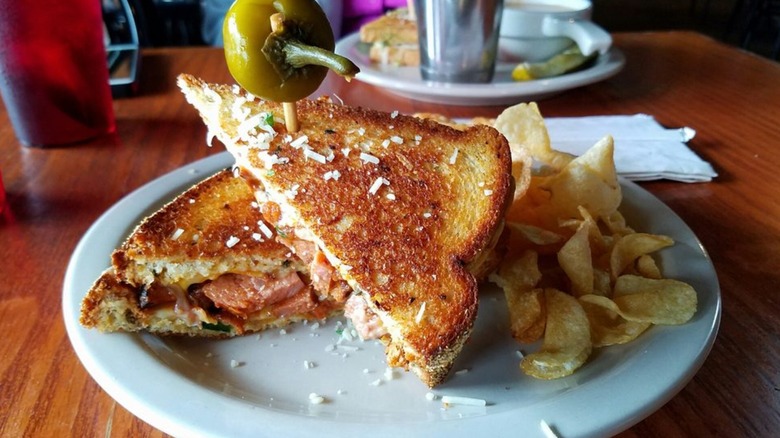 Ragin' Cajun sandwich topped with an olive skewer and plated with chips