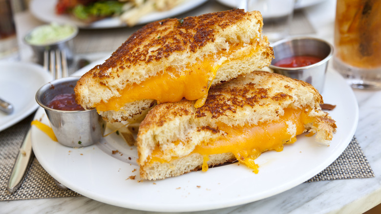 Grilled cheese sandwich sliced in half on a plate with ketchup and sauce at a restaurant
