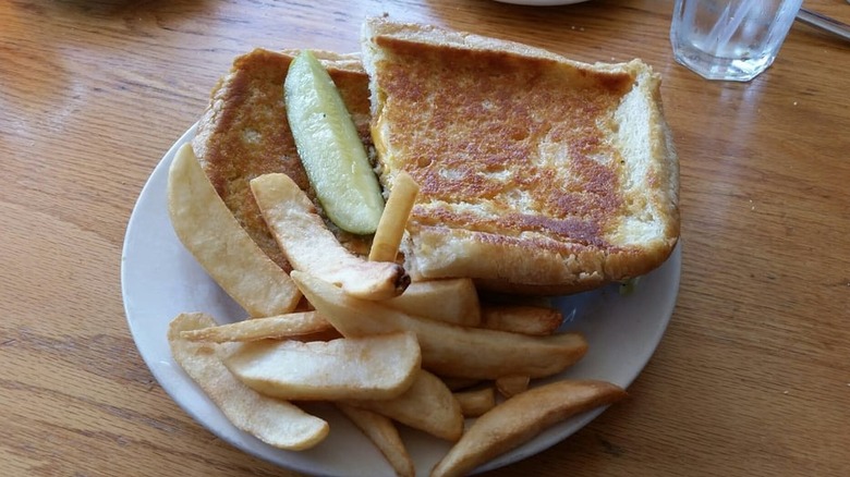 Welsh Rabbit grilled cheese with potato wedges and a pickle on a plate