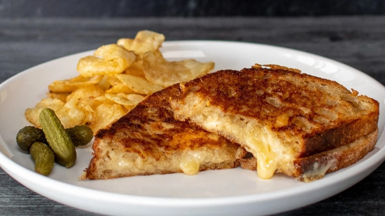Montana Gold grilled cheese on plate with chips and cornichons