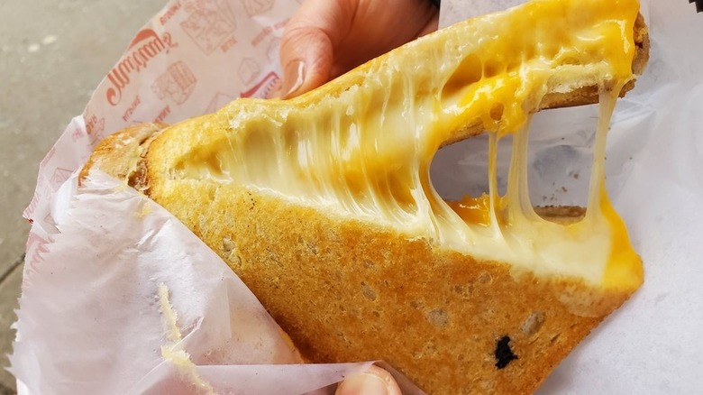 Hands pulling apart two halves of grilled cheese to show the cheese stretching