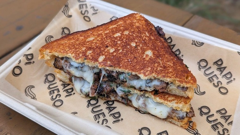 Texas Cheesesteak grillled cheese on tray lined with Papi Queso branded paper