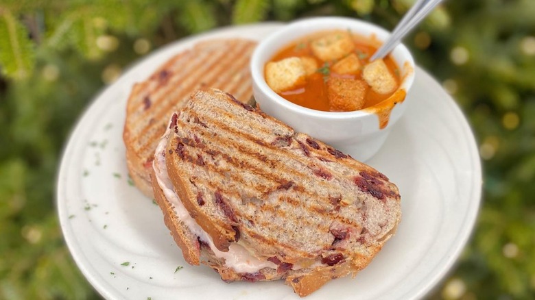 Two grilled cheese sandwiches and bowl of tomato soup topped with croutons on plate