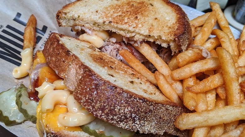 Macaroni Pony grilled cheese filled with macaroni, pork, and pickles, on tray alongside fries
