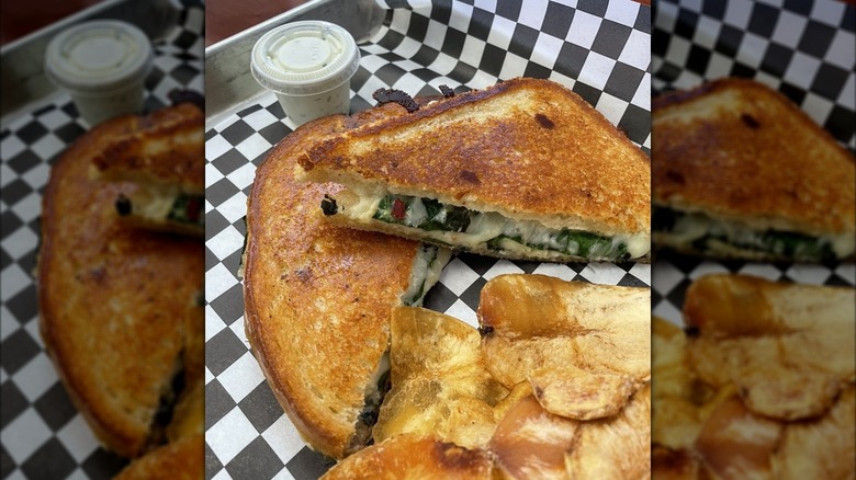 Spinach and artichoke grilled cheese, cut in half and served on tray with chips and dip