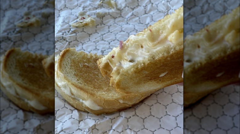 Grilled cheese cut in half, one slice held in air to show gooey filling