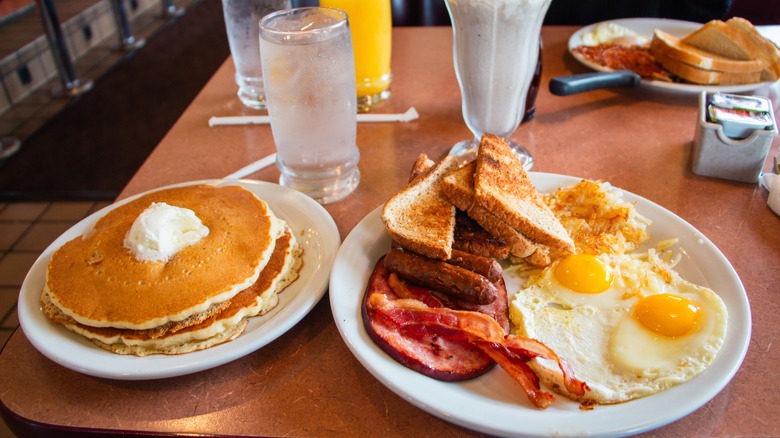 Pancakes, eggs, toast, and breakfast meats on a diner table
