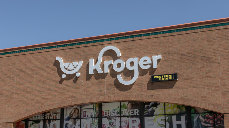 A zoomed in shot to the Kroger sign above a store with a smaller Western Union sign underneath