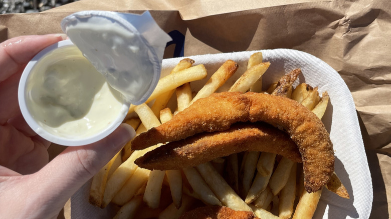 Fried fish and fries with tartar sauce on a paper bag