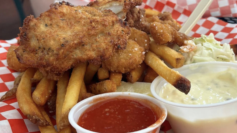 Fish and chips with condiments on red and white paper