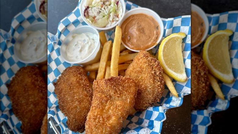 Fried fish and fries with sauces and slaw on paper
