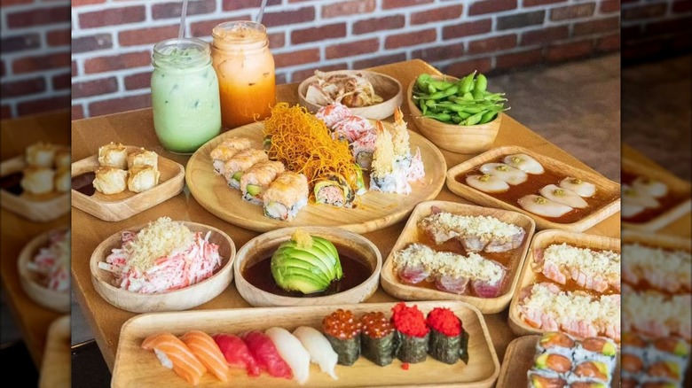 Sashimi, sushi, edamame, and drinks on wooden table