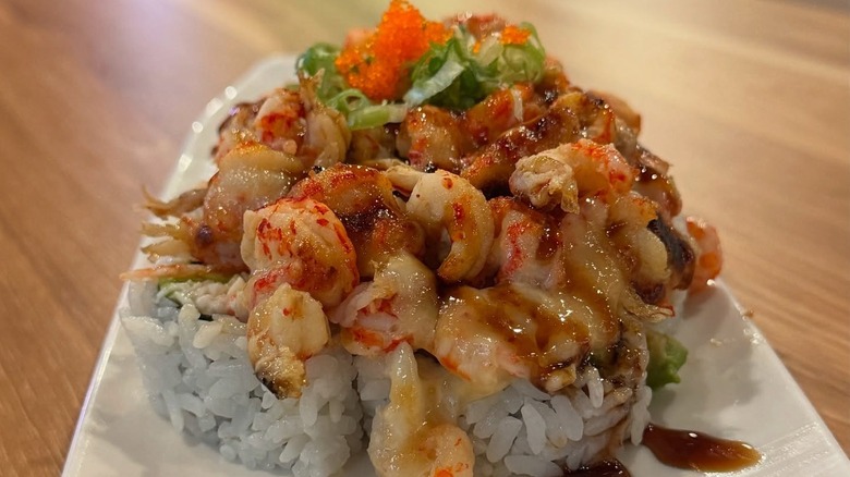 Sushi rolls topped with shrimp and tobiko on a white plate