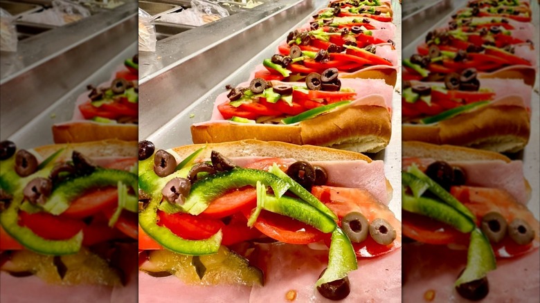 Open Italian sub with tomaotes and papers on paper outside with Amato's box