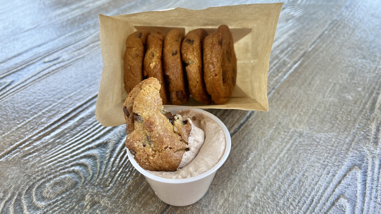Chocolate chip cookie dipped in chocolate hazelnut whip on a wooden table