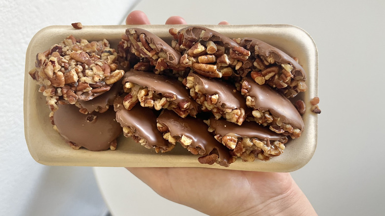 Close-up of a hand holding Nuttles chocolates on a tray