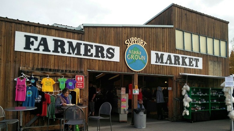 Exterior of Tanana Valley Farmers Market building with woman eating on picnic table outside