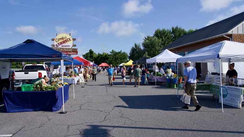 Shoppers walking amidst farmers market set up in parking lot