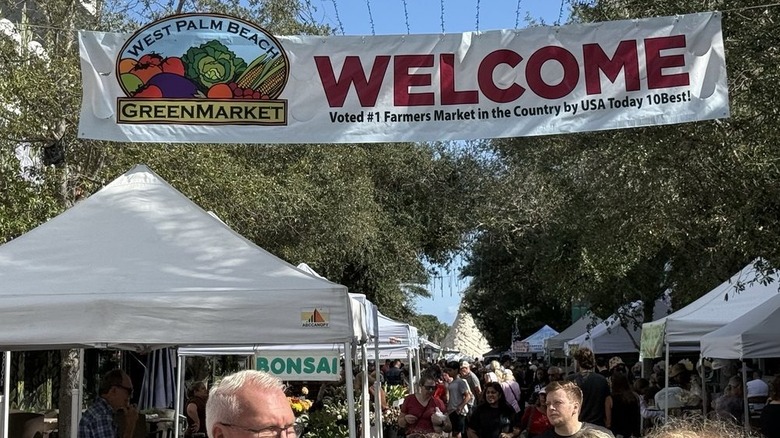 Shoppers strolling crowded street underneath welcome banner