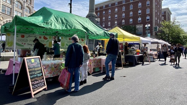 Shoppers browsing food stalls at farmers market on street in Troy
