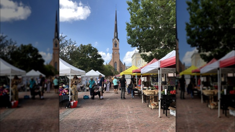 Steeple overlooking cobblestone expanse lined with farmers market tents