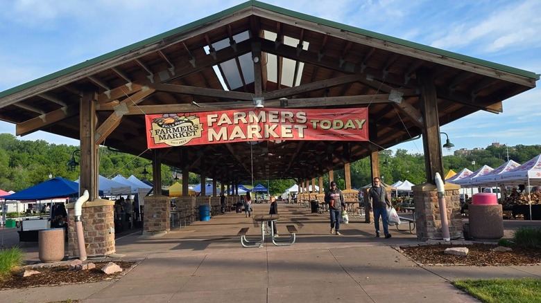 Shelter strung with banner advertising farmers market, tents on either side