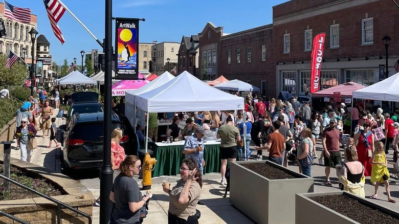 Crowded street lined with farmers market tents and American flags