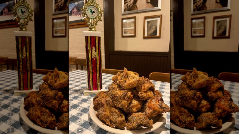 Plate of fried chicken next to trophy on white and blue tablecloth