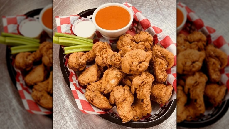 Close-up of a basket of fried chicken, celery sticks, and cup of sauce