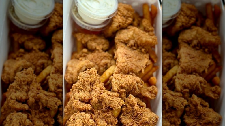 Close-up of pieces of fried chicken, sauce cup in background