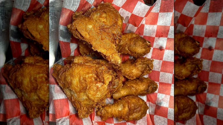 Top-down shot of pieces of golden brown fried chicken on top of red checkered paper