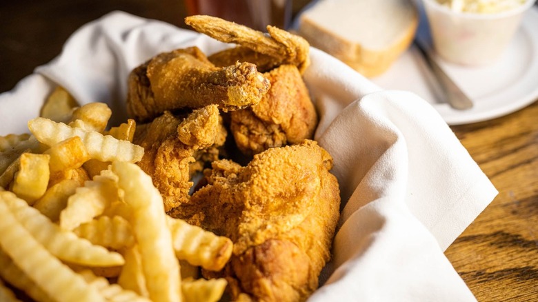 Close-up of cloth-lined basket holding fried chicken and crinkle cut fries