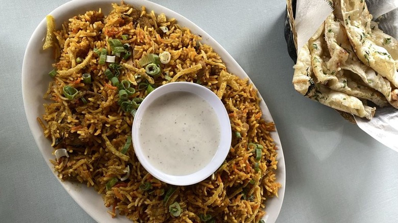 Overhead shot of naan, raita, and biryani