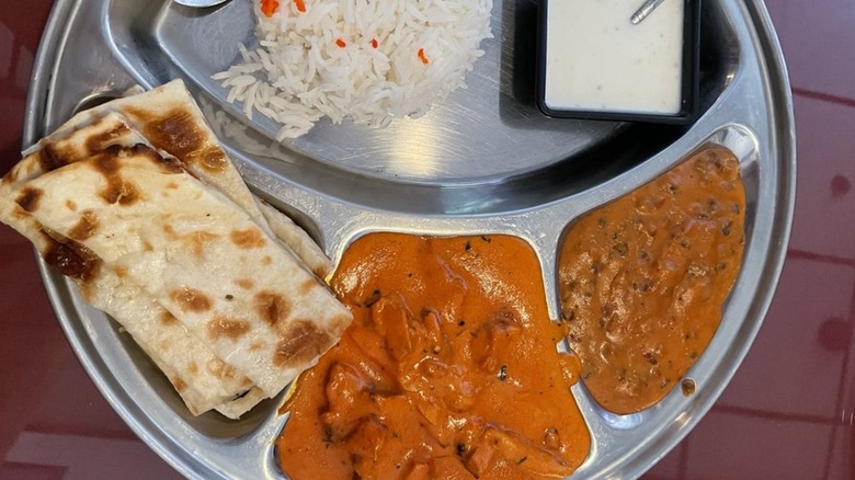 Butter chicken lunch combo with dal, naan, rice, and raita