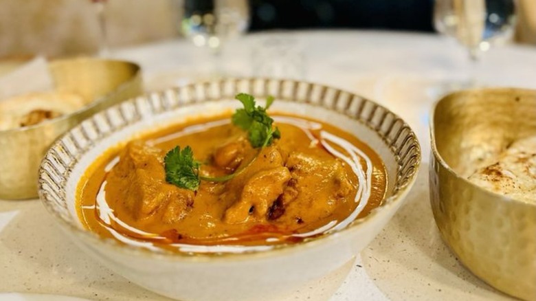 Meat-based curry in elegant bowl, drizzled with cream and garnished with cilantro
