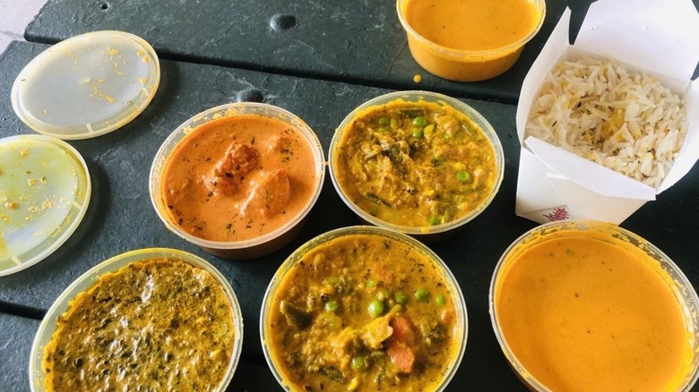 Takeout containers with various curries and one portion of rice