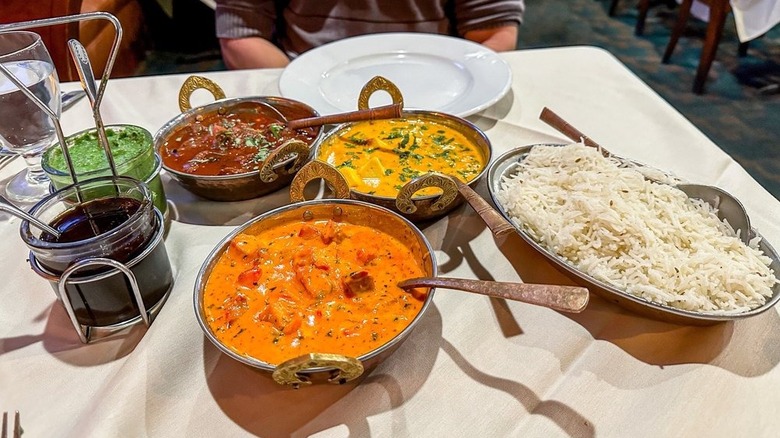 Rice, chutneys, and three curries on table laden with tablecloth