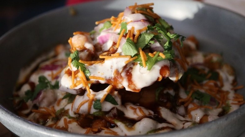 Samosa chaat topped with sev, onions, yogurt, and tamarind chutney