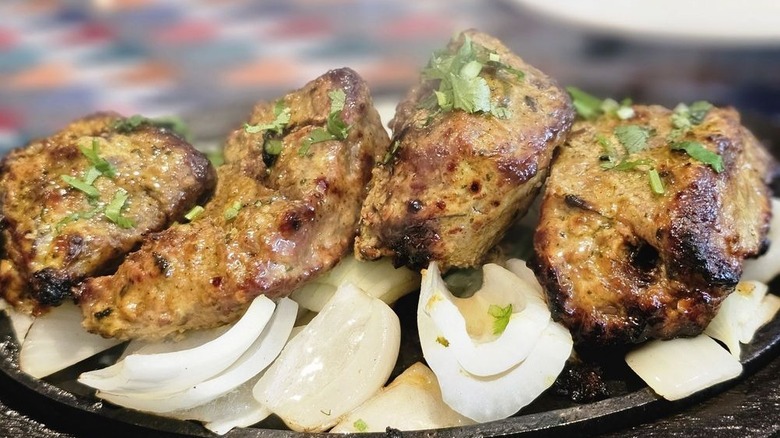 Lamb boti kabab on serving platter with chopped onions