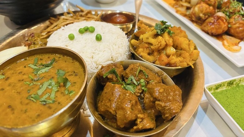 Thali with rice, vegetables, meat, dal, and dessert