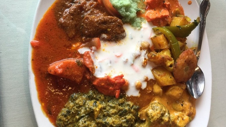 Several dishes from lunch buffet on plate, centered around serving of raita