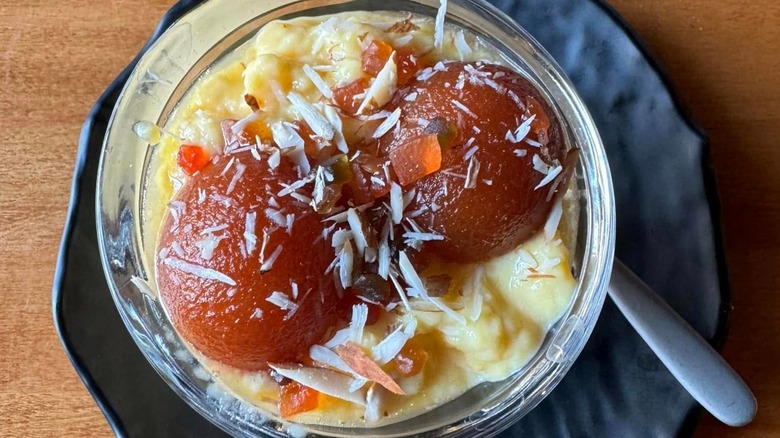 Two gulab jamun served in dish of custard