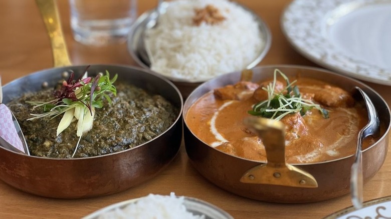 Lamb saag and chicken tikka masala in copper serving dishes alongside rice
