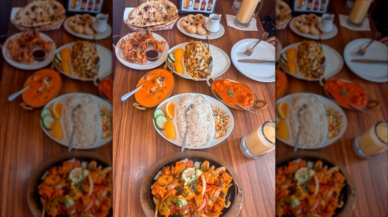 Table laden with garlic naan, mango lassis, and various curries and appetizers